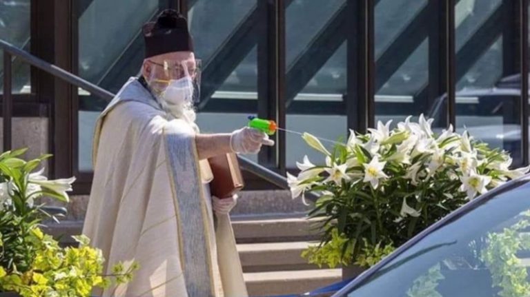 Un sacerdote utiliza una pistola de agua para bendecir a sus fieles manteniendo la distancia de seguridad