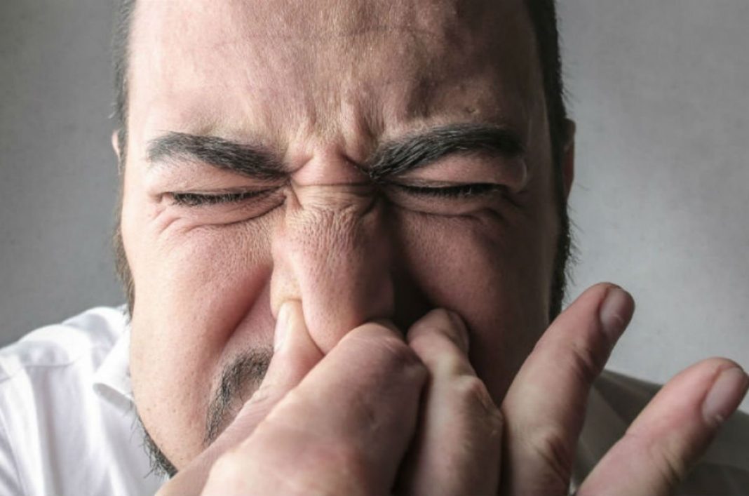 Hombre aguantando estornudo