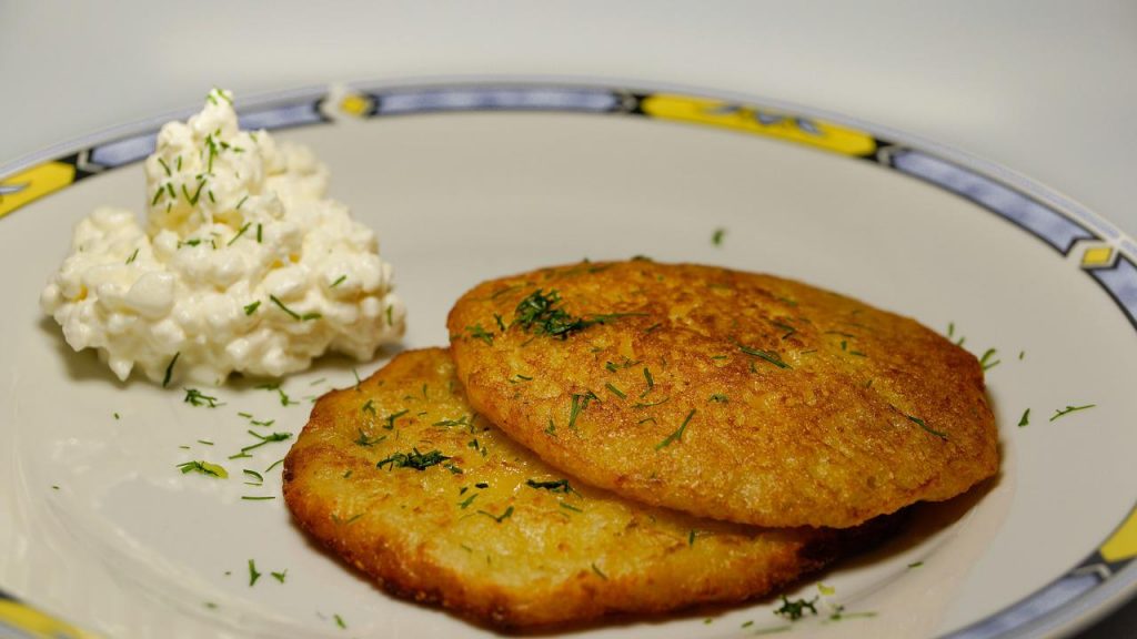 Las Tortitas De Fritas De Patata No Solo Las Puedes Comer A La Hora De Un Antojo, Sino Que También Quedan Perfectas Para Acompañar Platos Con Carne De Ave, Ternera O Cerdo Acompañadas De Una Rica Salsa. Preparar Estas Tortitas No Tiene Nada De Complicado Y El Sabor Divino Está Garantizado; Al Fin Y Al Cabo, Si Llevan Patatas, Nada Puede Salir Mal, Puesto Que Es Conocido El Rico Sabor Y Versatilidad De Este Tubérculo. No Te Pierdas Ningún Detalle Y Date El Gusto De Probarlas. Ingredientes Que Necesitas Para Preparar Tortitas Fritas De Patata Para La Preparación De Las Más Ricas Tortitas Fritas De Patata, Necesitas Pocos Ingredientes; Y De Hecho, Estos Son Los Más Tradicionales, Los Que Son Básicos En El Menú Familiar. Por Lo Tanto, Hacerlas No Solo Te Permitirá Disfrutar De Un Rico Plato, Sino También, Tendrás La Oportunidad De Preparar De Manera Diferente Esos Ingredientes Que Ya Tienes En Casa. Los Ingredientes Que Vas A Necesitar Para Prepararlas Son: 4 Patatas Grandes, 2 Huevos, 1 Cebolla, 2 Cucharadas De Harina, Sal, Pimienta, Perejil En Polvo Y Aceite De Oliva Virgen Extra. Comienza Preparando Las Patatas Lo Primero Que Debes Hacer Es Preparar Las Patatas Para Poder Utilizarlas En Esta Receta, En La Que Este Tubérculo Es El Protagonista. Lava Muy Bien Las Patatas, Retírales La Piel Y Pásalas Por Un Rallador. Puedes Rallarlas Del Grosor Deseado; Aunque Por Supuesto, El Más Común Es El De Grosor Medio; Puesto Que De Esta Manera, Quedarán Perfectas Para Armar Las Tortitas, Pero A La Vez Se Sentirán En Cada Mordida. Prepara La Cebolla La Presencia De La Cebolla En Las Preparaciones Con Patatas, Son Definitivamente Un Plus Que Aporta Un Rico Sabor Y Mejora Considerablemente El Resultado Del Plato, Haciéndolo Más Rico Y Con Un Sabor Más Dulzón. En Caso De Que No Te Agrade La Idea De Añadir Cebollas, Puedes Evitar Este Ingrediente; Sin Embargo, Te Invito A Probarlas Para Que Descubras Por Ti Mismo El Rico Sabor Que Aportan. En Caso De Añadirla, Pélala Y Pásala Por El Rallador Para Que Quede Tan Pequeña Como La Patata. Así Se Prepara La Base Para Estas Tortitas Fritas De Patata Una Vez Que Tengas Las Patatas Y La Cebolla Perfectamente Ralladas, Pon Ambas En Un Colador Y Con La Ayuda De Tus Manos Presiona Para Eliminar El Exceso De Humedad De Ambos Ingredientes. Eliminar El Exceso De Agua Es Necesario, Pues De No Hacerlo, Será Necesario Añadir Más Harina, Lo Cual Hará Que No Se Disfrute Bien El Sabor De La Patata En Estas Tortitas. Prepara La Masa Para Las Tortitas Cuando Tengas Listas Las Patatas Y La Cebolla, Ponlas Bien Escurridas En Un Bol Y Añade La Harina, Huevo, Perejil En Polvo Y Sal Y Pimienta A Tu Gusto. Mezcla Muy Bien Todos Los Ingredientes. No Es Necesario Añadir Demasiada Harina, Ya Que El Huevo Y También El Propio Almidón De Las Patatas Actuará Para Hacer Que Las Tortitas Permanezcan Bien Compactas Al Momento De Llevarlas A Freír. Es Por Esto Que Es Necesario Eliminar El Agua Excedente Antes De Mezclar Todos Los Ingredientes. Alista La Sartén A La Hora De Freír, Lo Más Común Es Utilizar Una Cantidad Generosa De Aceite; Sin Embargo, En Este Caso, Lo Mejor Será Poner Solo Un Poco De Aceite. Pon Una Sartén Al Fuego Medio Y Vierte Un Poco De Aceite De Oliva Virgen Extra; El Cual, Como Sabes, Es El Más Recomendado Para La Fritura De, No Solo Estas Tortitas Fritas De Patata, Sino También Croquetas, Pescados Y Más. Espera Que Tome Temperatura Antes De Poner A Freír Las Tortitas. Así Se Fríen Las Tortitas Cuando El Aceite De Oliva Virgen Extra Esté Caliente, Comienza A Darle Forma A Las Tortitas Y Ponlas A Freír. No Las Hagas Demasiado Grandes, Pues De Un Tamaño Mediano Quedan Más Bonitas A La Vista Y Son Más Fáciles De Comer. Coloca Unas Dos O Tres A Freír Y Espera Que Tomen Color Antes De Voltearlas. Termina De Prepararlas Y Disfruta Una Vez Que Observes Que Las Tortitas Fritas De Patata Lucen Doraditas, Dales La Vuelta Y Termina De Freírlas Para Que Estén Igual De Doradas Por Ambas Caras. Cuando Las Retires De La Sartén, Llévalas A Un Plato Con Papel Absorbente Para Eliminar El Exceso De Grasa Que Puedan Tener. Termina De Hacer Las Siguientes Y Sírvelas Calientes Para Que Puedas Disfrutar De Toda Su Textura Crujiente, Apenas La Tengas Listas. Ingredientes Que Puedes Utilizar Para Darles Más Sabor A Estas Ricas Tortitas Fritas De Patata, La Cebolla Y El Perejil Le Dan Un Sabor Exquisito; Ahora Bien, Puedes Añadir Otros Ingredientes Para Aromatizarlas Y Lograr Un Plato Realmente Único Que Combine Con Lo Que Desees Acompañarlas. Puedes Añadir Un Poco De Ajo En Polvo O Un Poco De Ajo Natural Finamente Picado. También, Si Te Gusta El Picante, Eres Libre De Añadir Un Toque De Guindilla Para Que Queden Picositas. Con Relación A Las Hierbas Que Puedes Incorporar, El Orégano, Romero O Cebollino, Les Darán Mucho Sabor. Cómo Lograr Tortitas Fritas De Patata Perfectas Para Lograr Que Las Tortitas Fritas De Patata Queden Bien Compactas, Lo Mejor Es Utilizar Unas Buenas Patatas Que Tengan Una Cantidad De Almidón Adecuada. Si Usas Patatas Nuevas, Estas Tendrán Menor Cantidad De Este Elemento Que Actúa Como Aglutinante Y Reduce La Cantidad De Harina A Añadir. Al Momento De Freírlas, Recuerda Ponerlas En Pequeñas Cantidades Para Evitar Las Drásticas Fluctuaciones De Temperatura En El Aceite. También, Recuerda Hacerlas De Un Tamaño Más Bien Pequeño O Mediano Para Que Resulten Perfectas Para Comer. Si Disfrutas Las Recetas Originales Con Patatas, Conoce Esta Receta Viral Que Te Hará Comerlas Con Frenesí. Y Además, Aprovecha También Esta Receta Para Prepararlas Al Ajillo Y Ten Lista La Guarnición Perfecta Para Carnes En Unos Minutos.