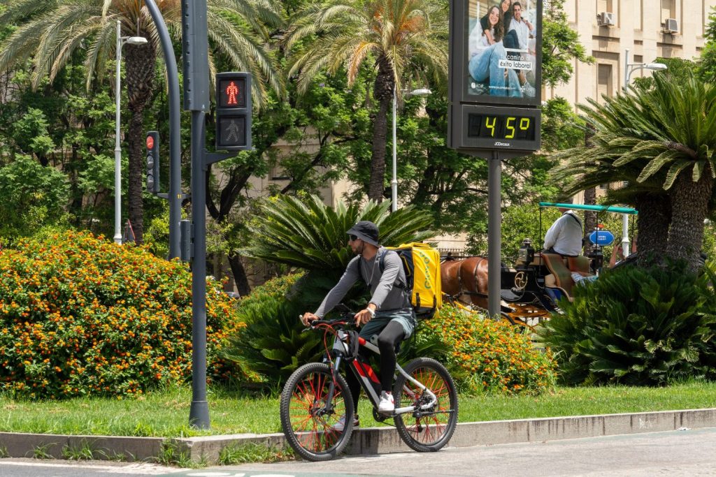 Un Repartidor De Glovo Reparte Comida A Domicilio En Bicicleta A 45 Grados En La Ciudad De Sevilla